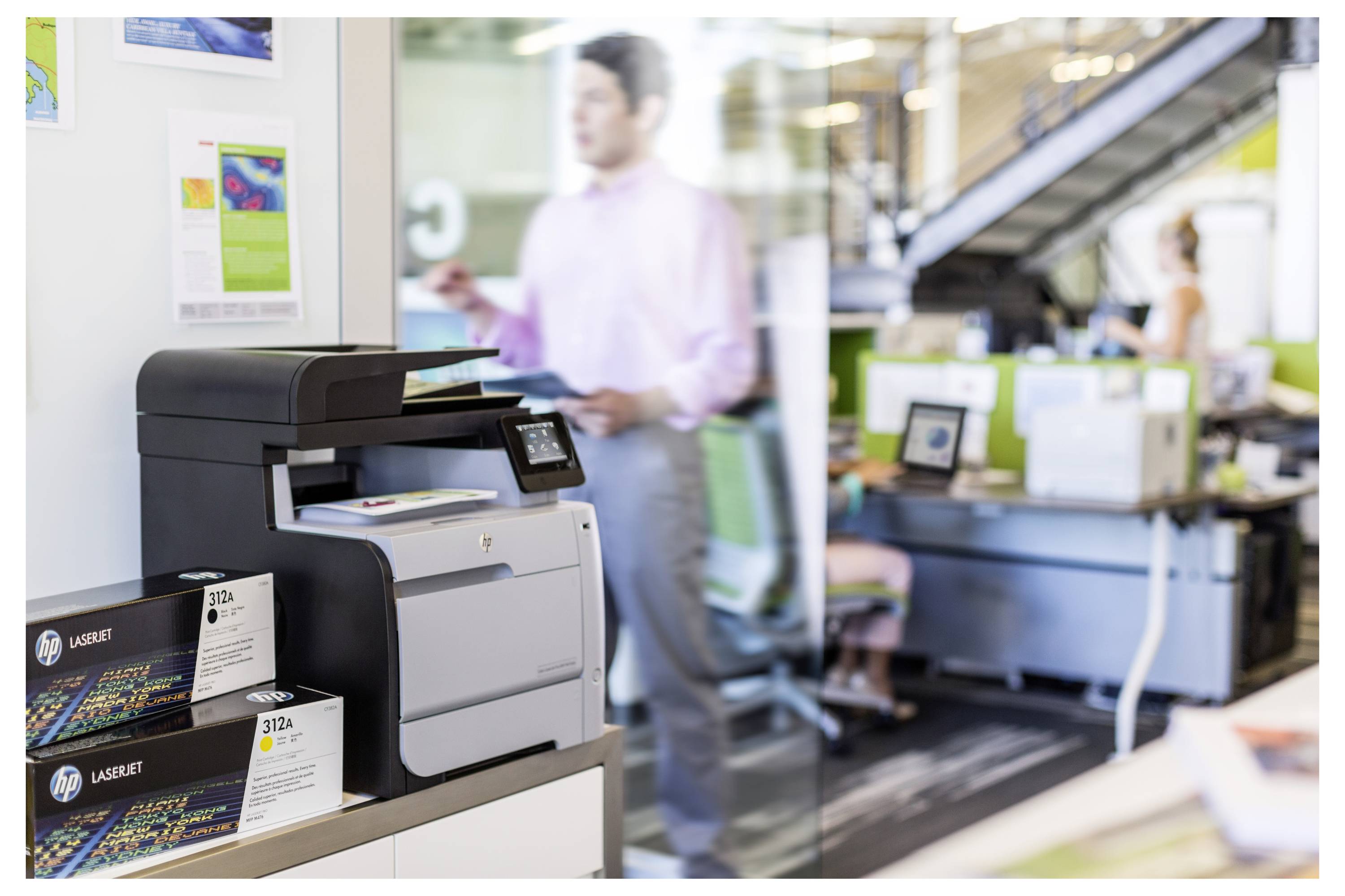 HP LaserJet-printer op een displaytafel in een kantoorshowroom, met productkaarten en mensen die in de onscherpe achtergrond werken.