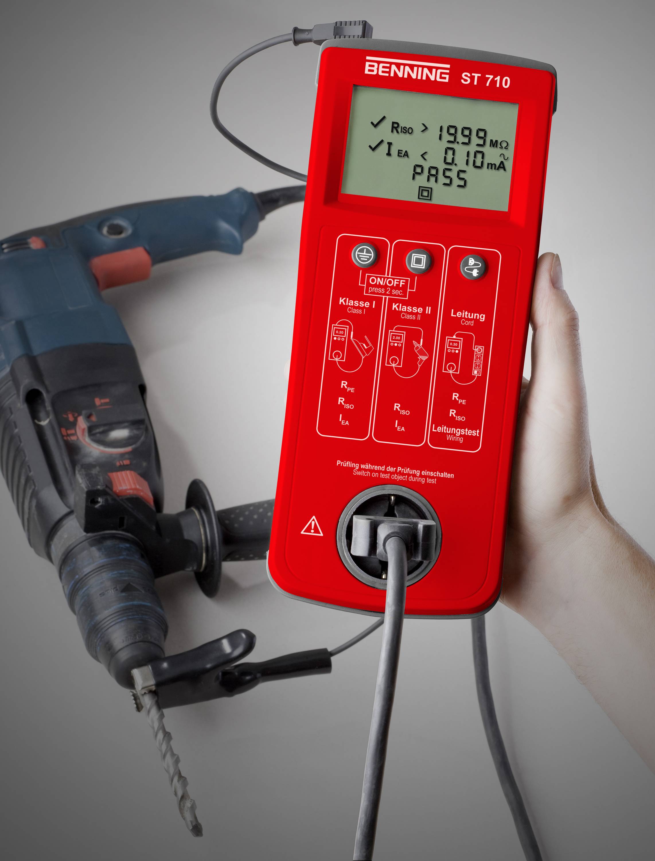 Een handapparaat voor elektrische veiligheidsinspectie toont '1999 mΩ PASS'. Het test een aangesloten boormachine op veiligheid.