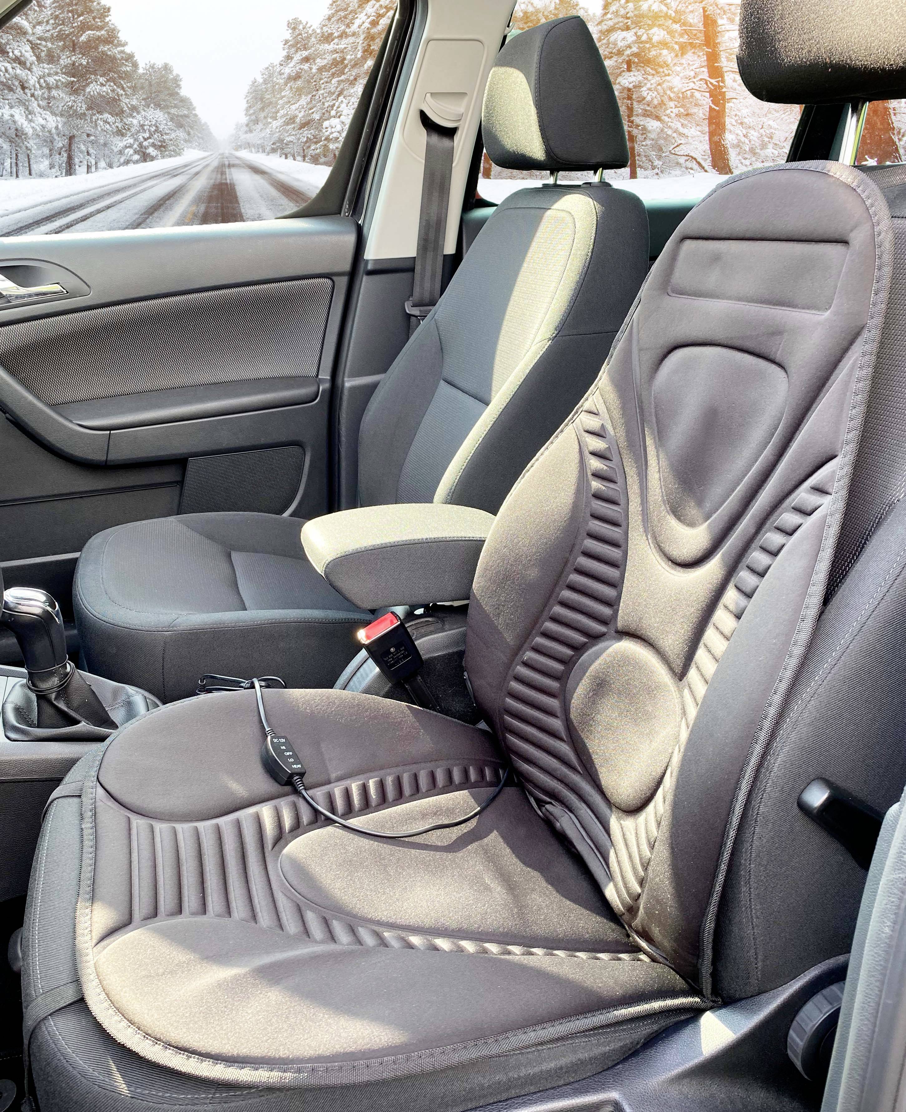 Het interieur van een auto met ergonomische stoelkussens waaruit verwarmingskabels zichtbaar lijken te zijn. Door het raam ziet men een besneeuwde weg.