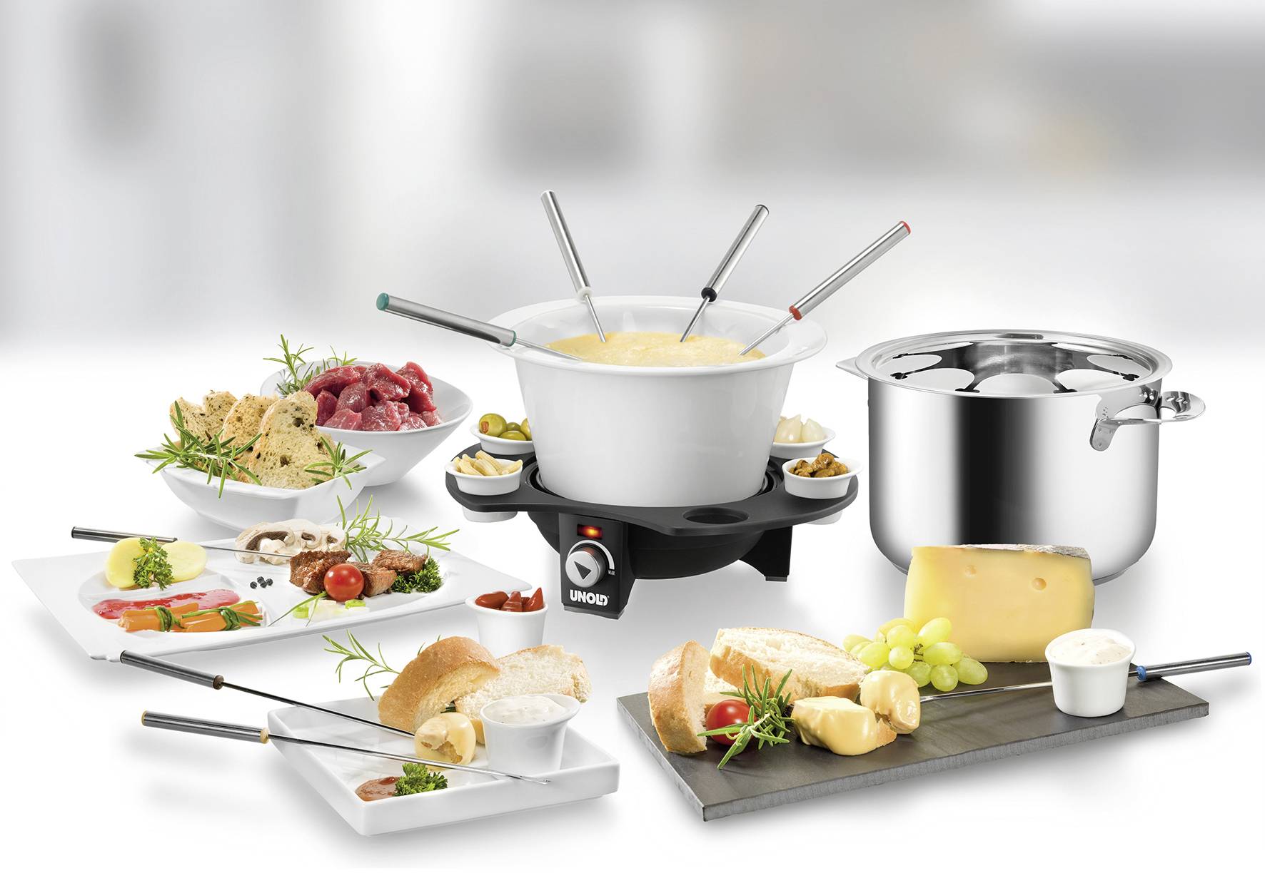 Fonduestel met verschillende ingrediënten: kaas, brood, vlees, aardappelen, groenten op borden; elektrische kookplaat met fonduepan.