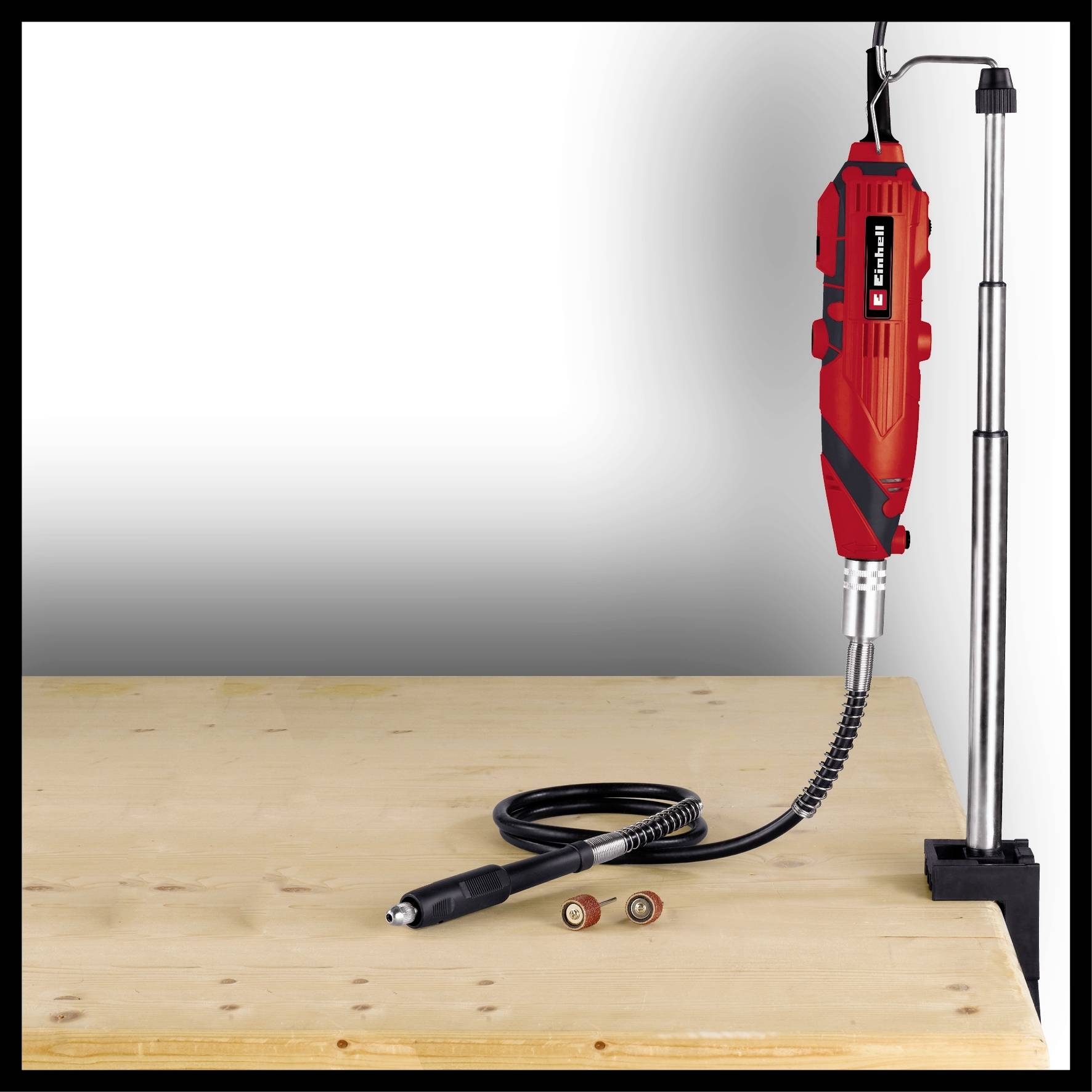 Een rood multitool met een flexibele schacht, gemonteerd op een houten plank. Ideaal voor precisie-klusjes en modelbouwprojecten.