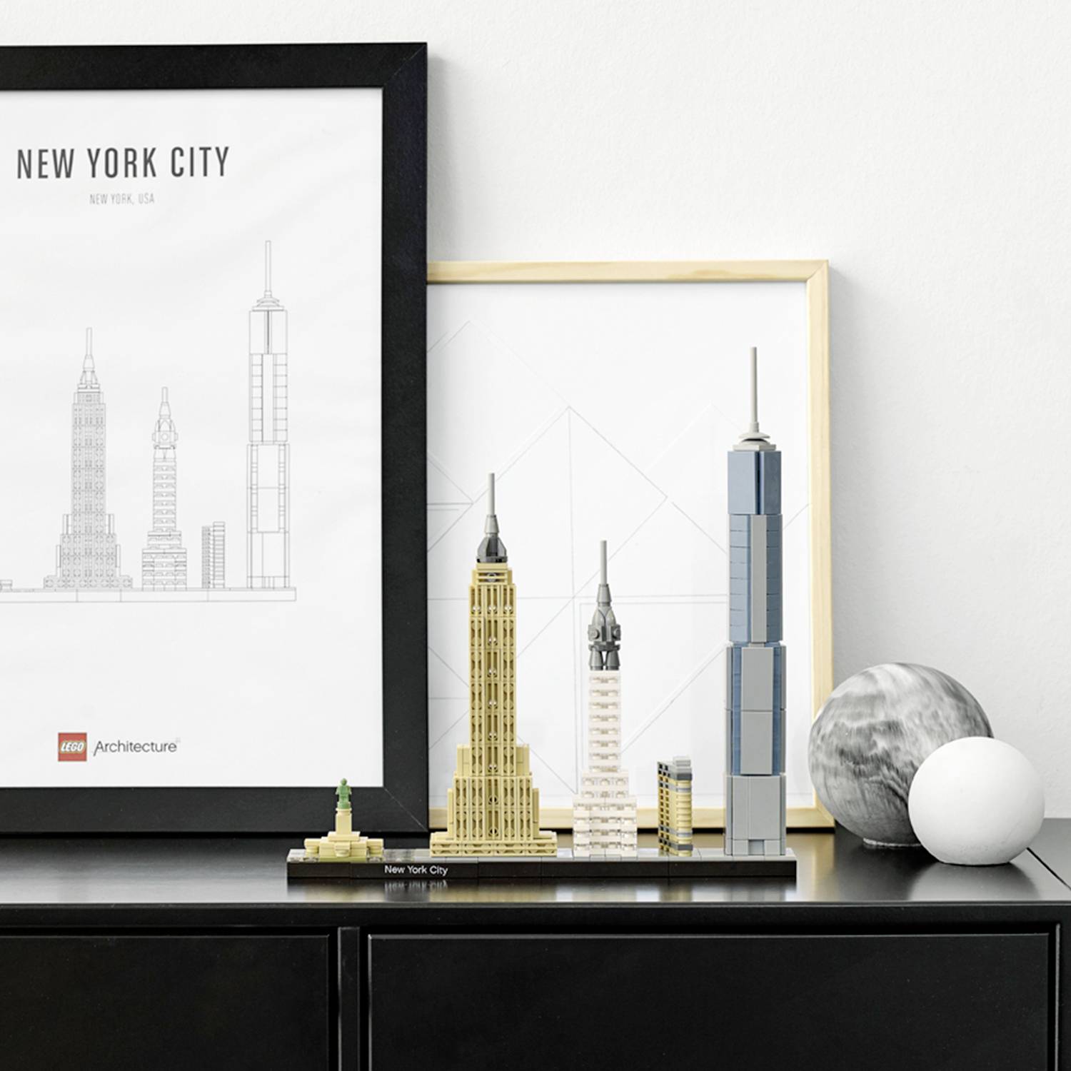 LEGO-architectuurset van New York City met modellen van gebouwen op een plank. Daarachter een ingelijste, minimalistisch geschetste skyline.