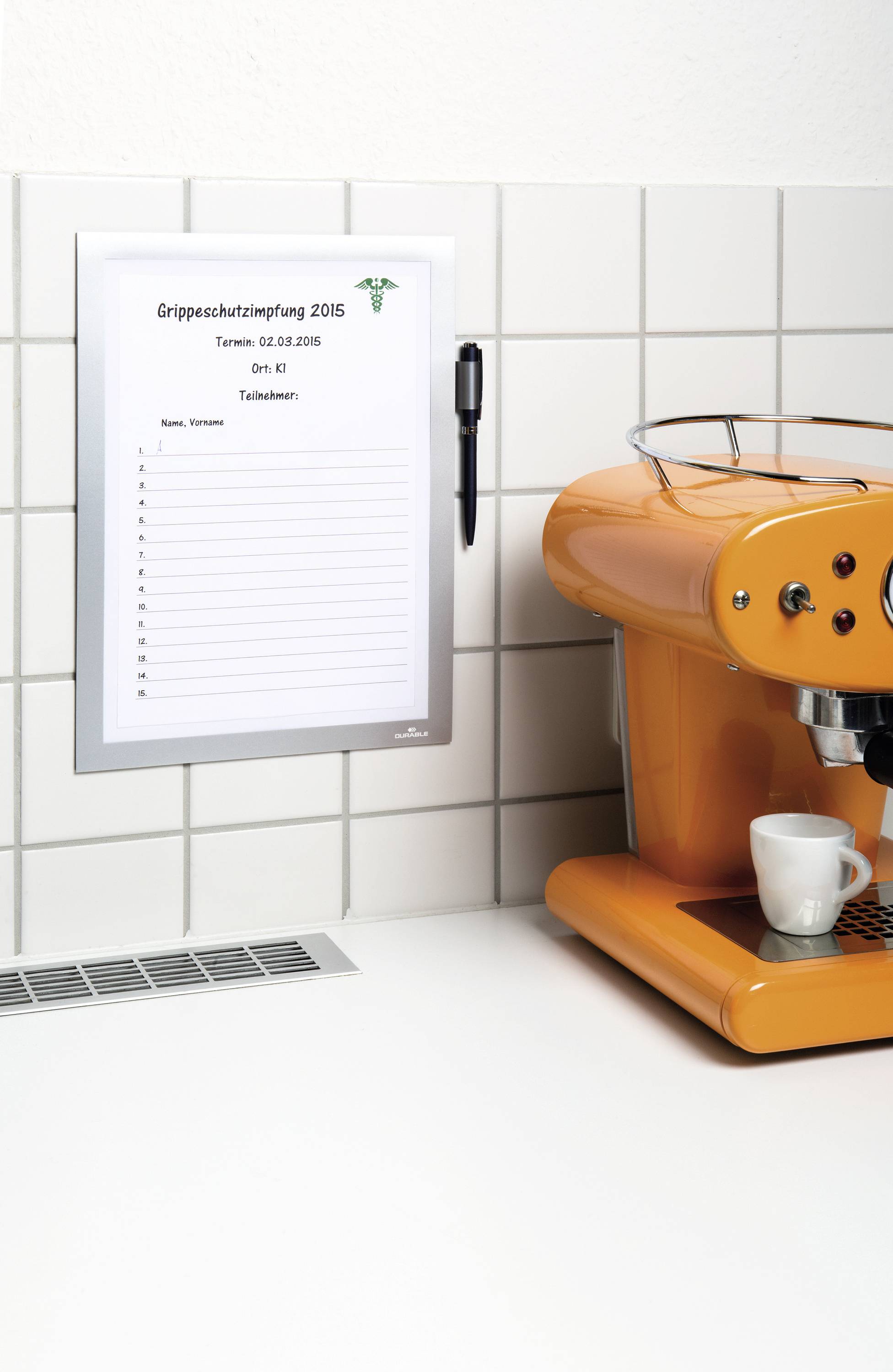 Notitie aan tegelwand toont afspraak voor 'Griepvaccinatie 2016' op 5-01-2016, locatie: begane grond. Ernaast staat een oranje koffiemachine.