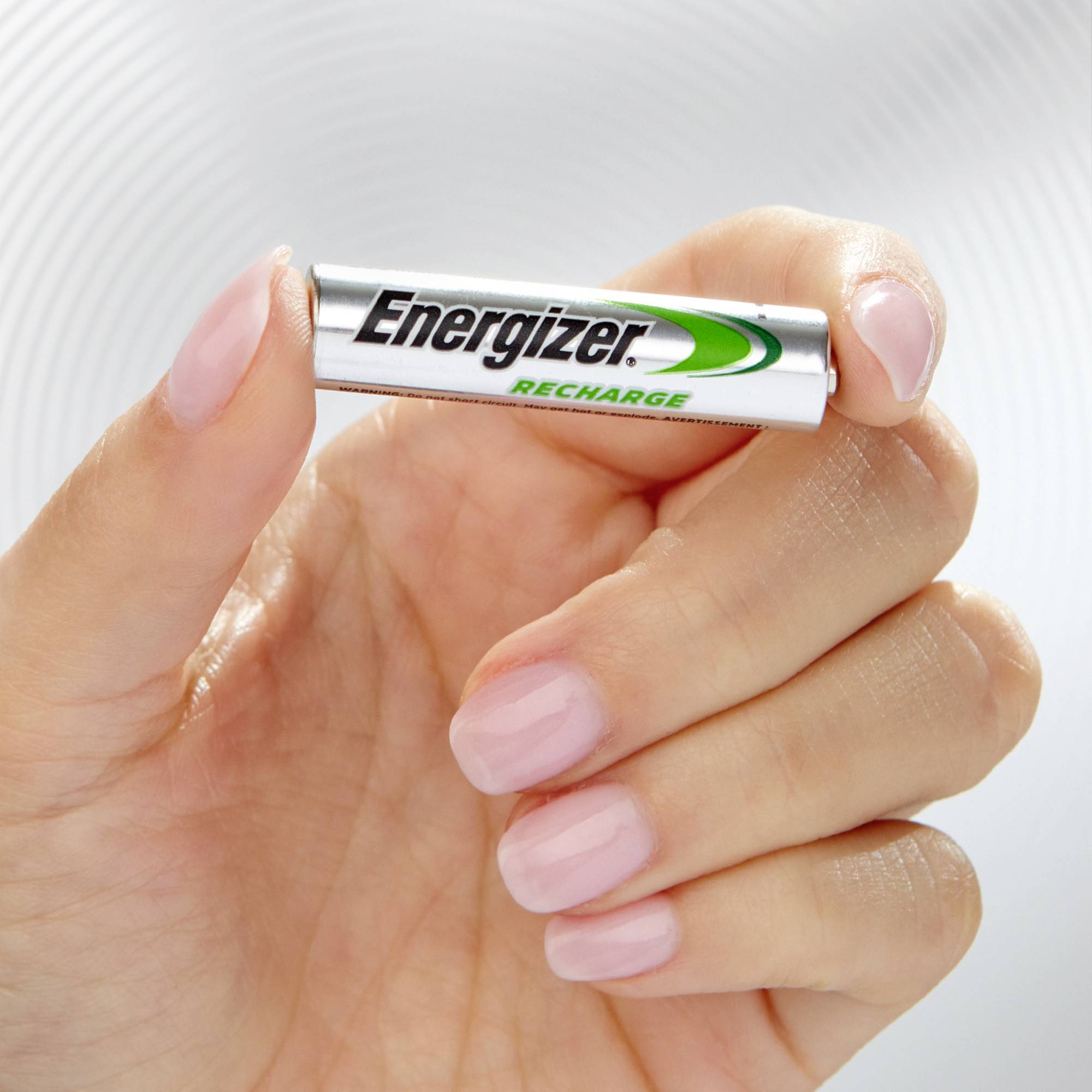 Een hand houdt een 'Energizer Recharge'-batterij voor een neutrale achtergrond.