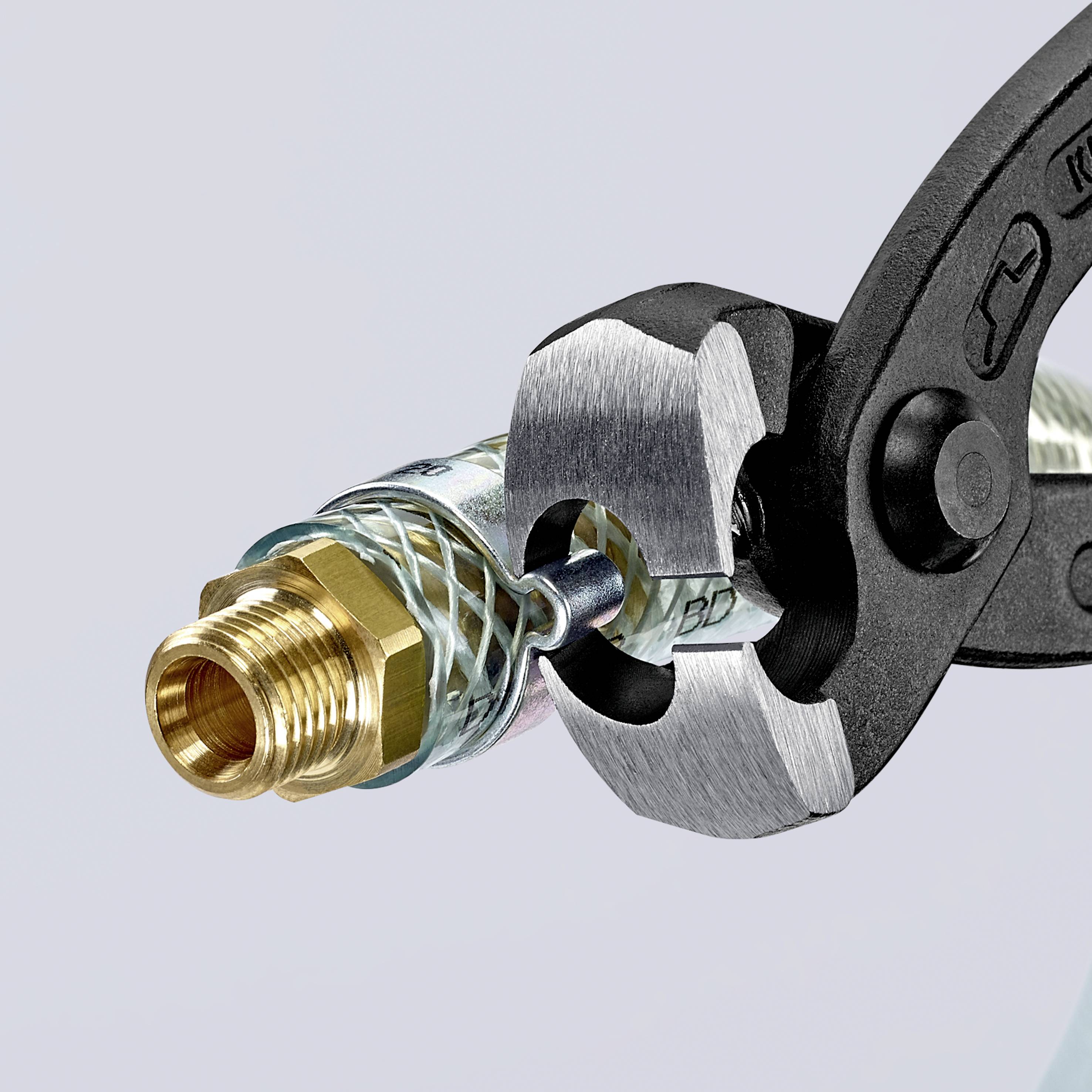Een tang snijdt een metalen buis met een messing aansluiting door. De afbeelding toont het moment vlak voordat de buis wordt doorgesneden.