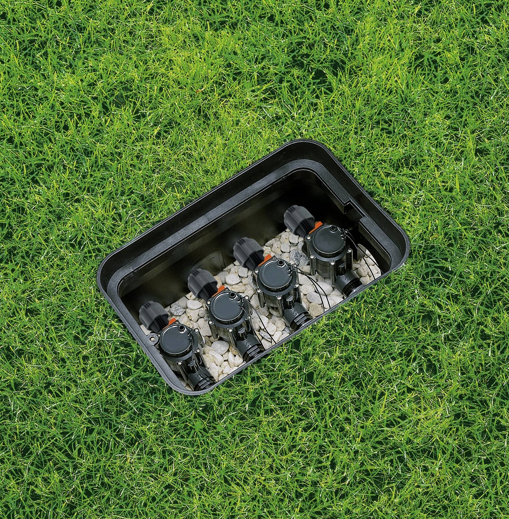 'Een zwarte doos met vijf wateraansluitingen is ingegraven in een grasveld.'