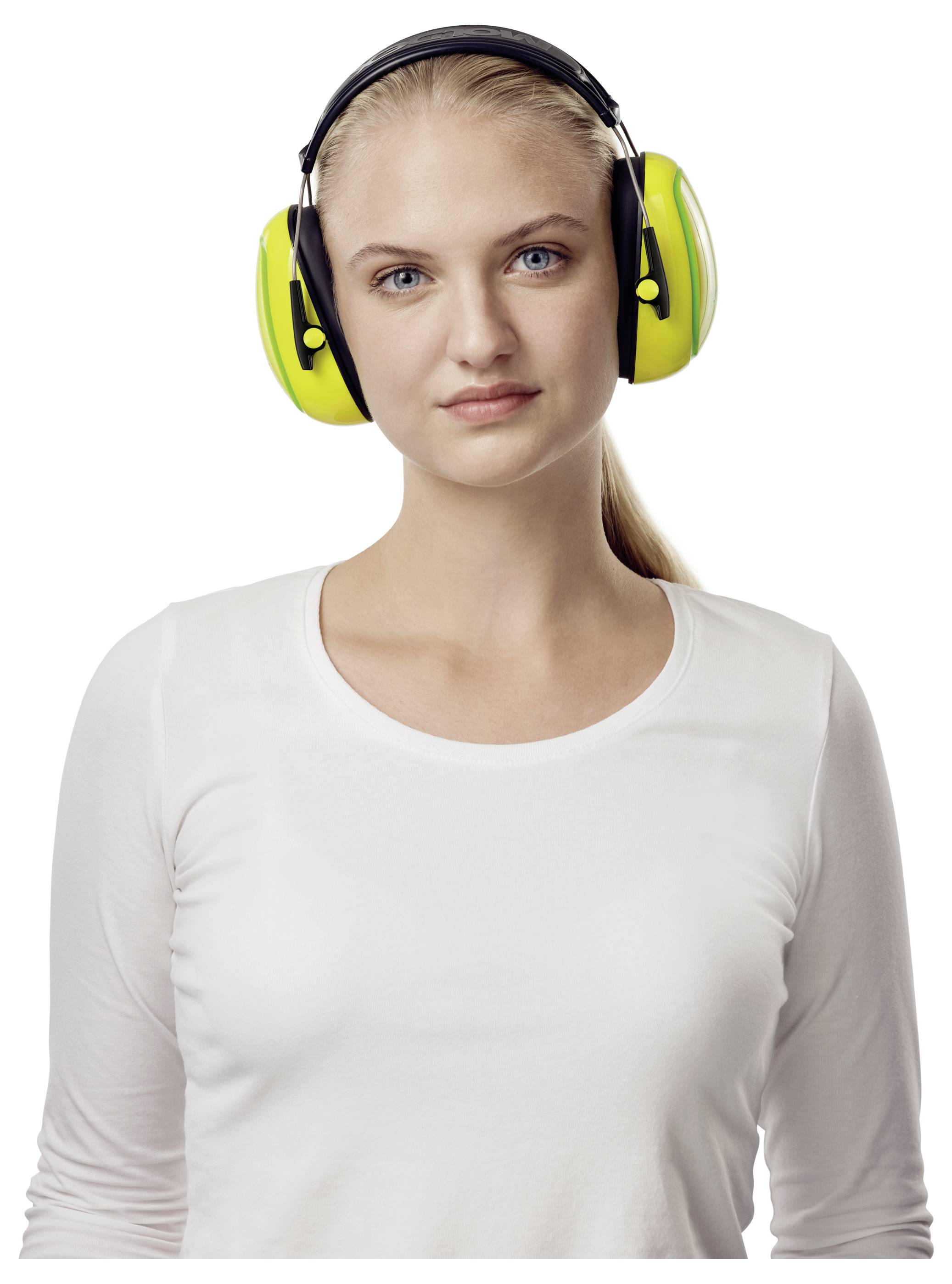 Een persoon die geluidsdemper oorbeschermers draagt en een wit overhemd aanheeft, staat tegen een eenvoudige achtergrond en kijkt rechtstreeks in de camera.