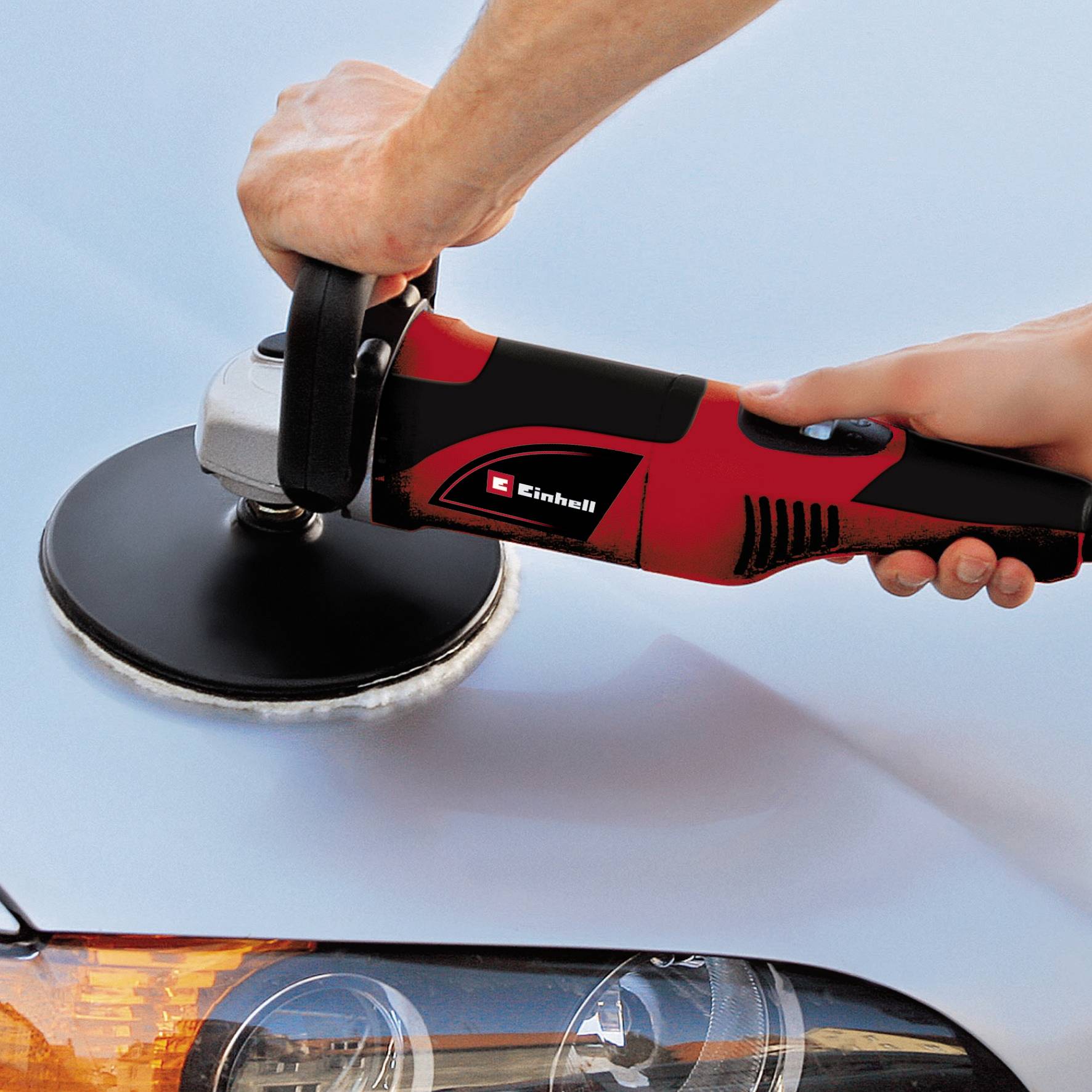 Een hand polijst een autooppervlak met een elektrische polijstmachine om de glans van de autolak te verbeteren.