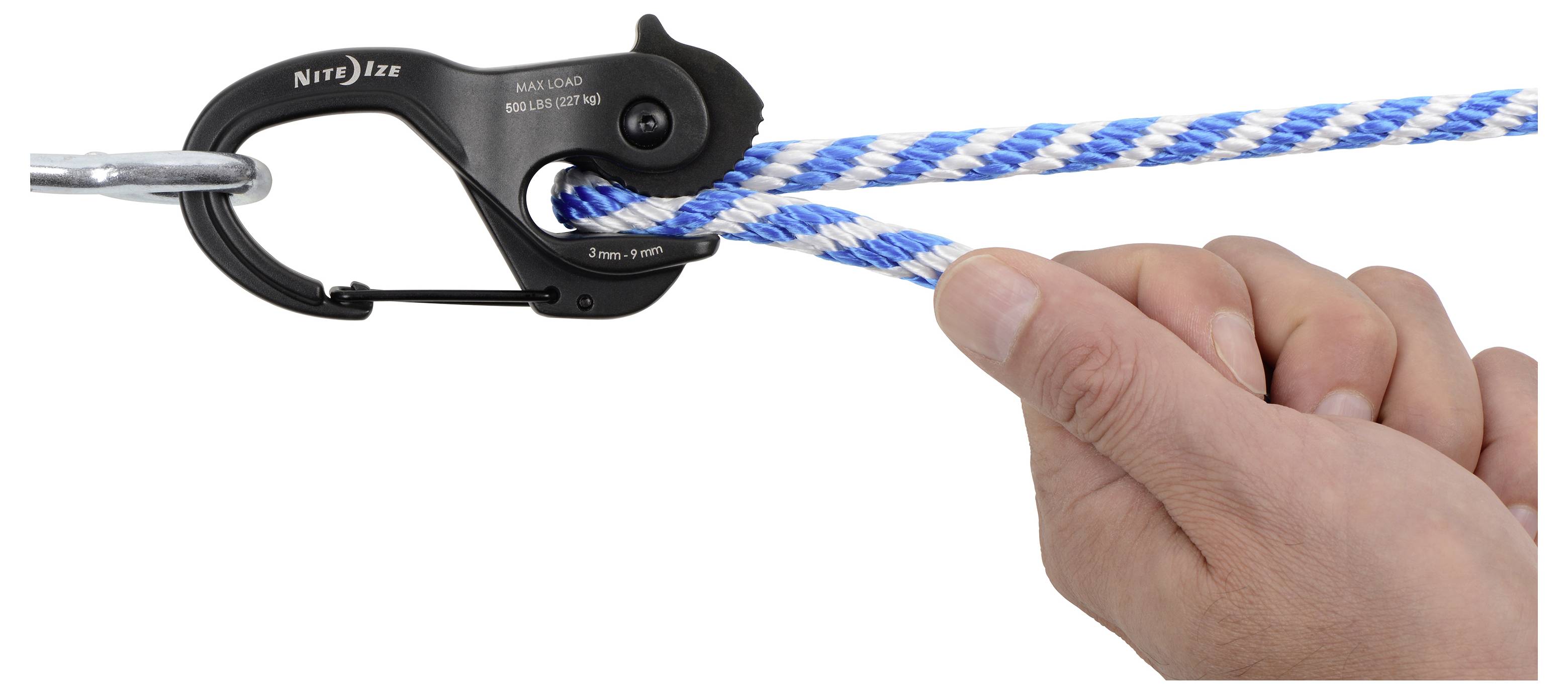 'Een hand houdt een blauw en wit touw vast, bevestigd met een zwarte metalen clip gelabeld als Nite Ize.'