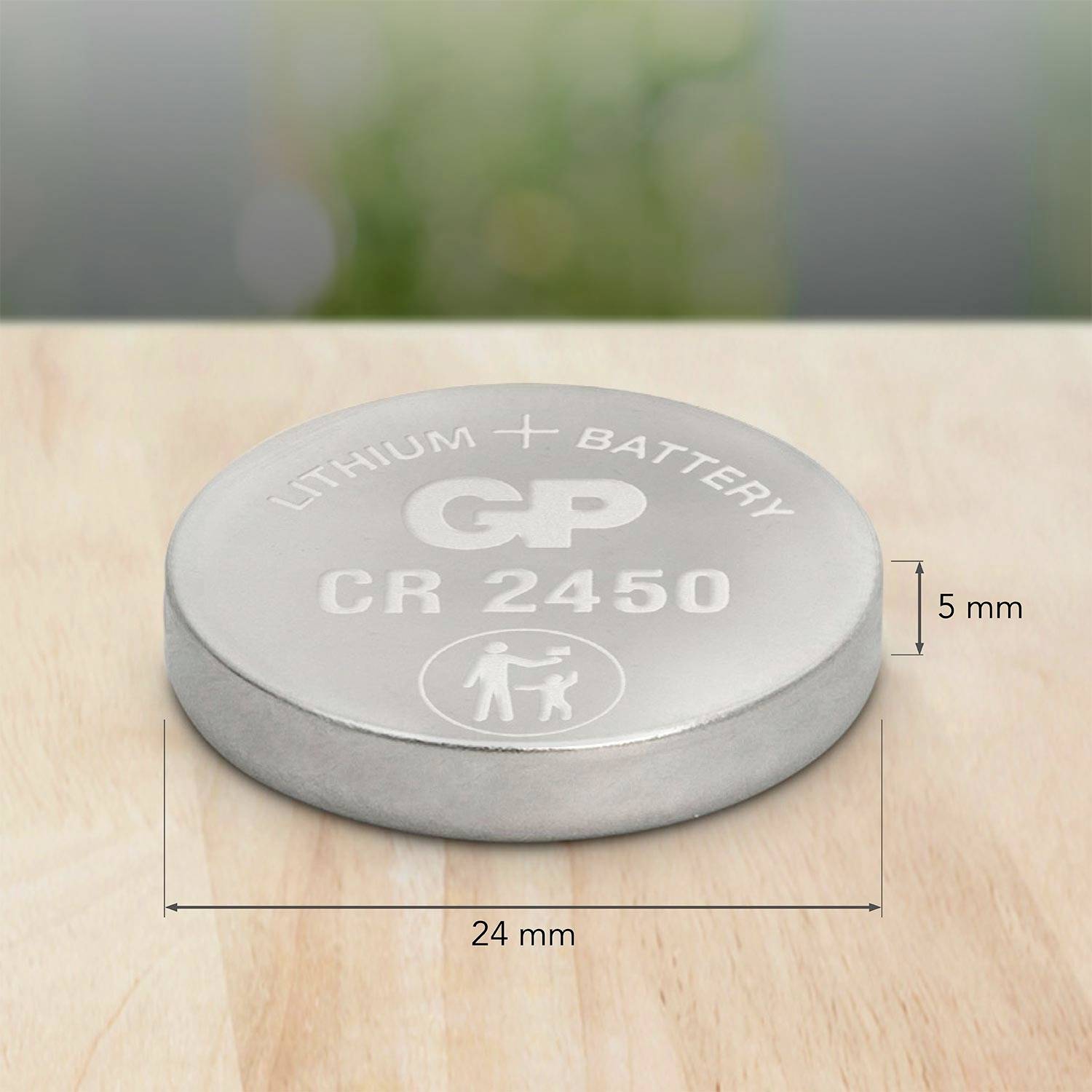 Zilveren knoopbatterij met opschrift 'Lithium Battery GP CR 2450', op houten tafel. Diameter: 24 mm, hoogte: 5 mm.