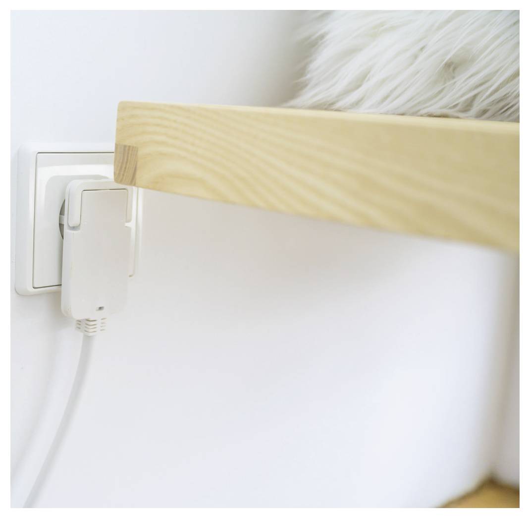 Houten meubels dicht tegen een wandcontactdoos met een ingestoken lader, wat een beperkte stroomverbinding toont.