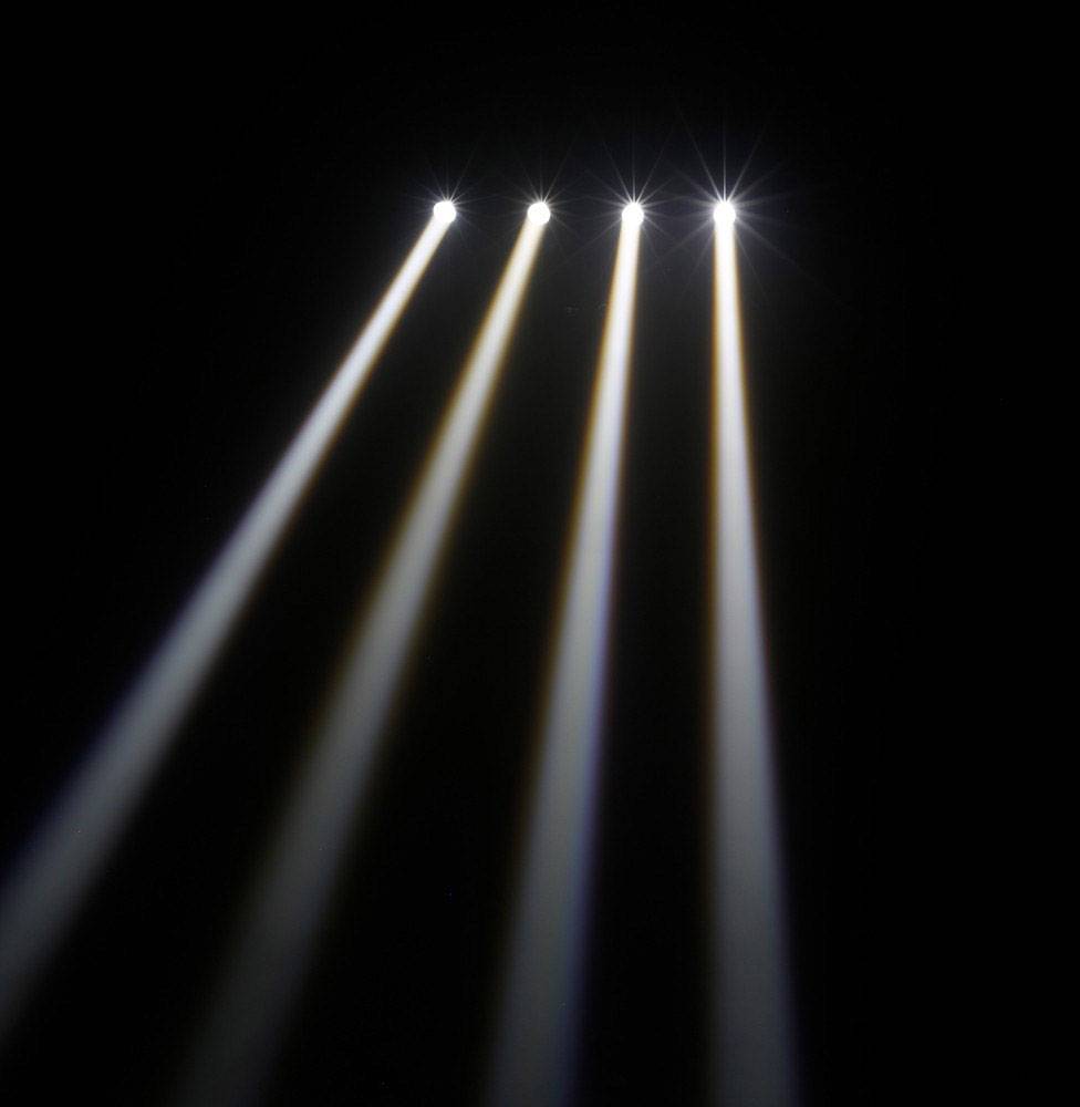Vier sterke lichtstralen die diagonaal van bovenaf op een donker oppervlak schijnen. De stralen zijn parallel en gelijkmatig verdeeld.