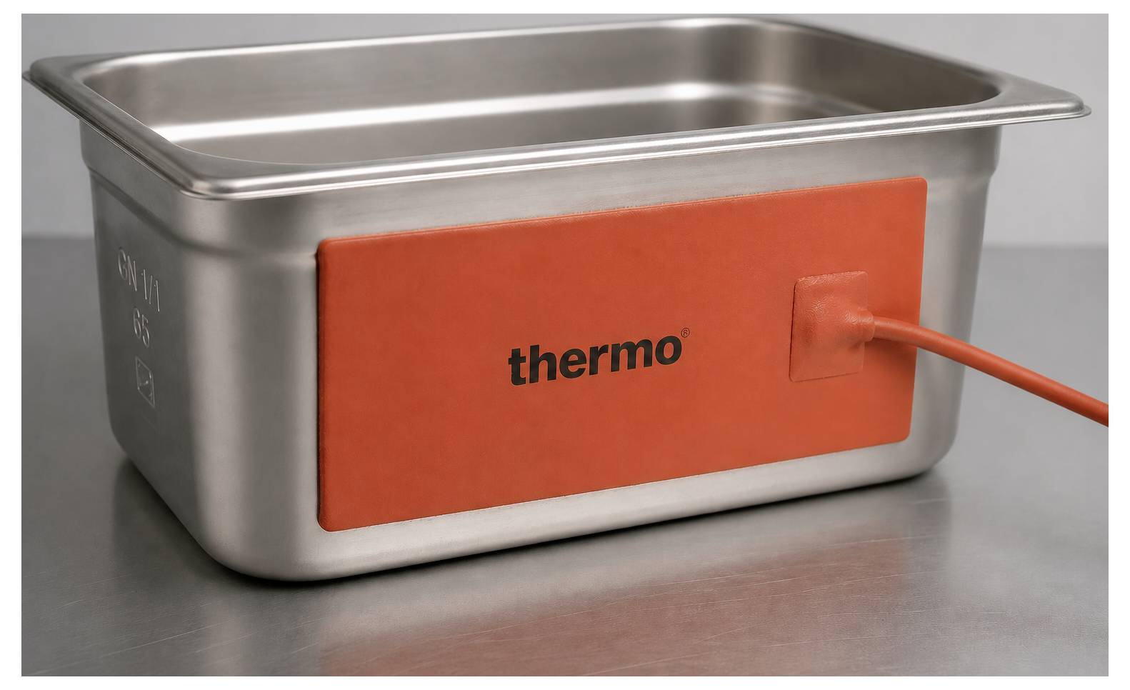 Roestvrijstalen voedselbak met oranje 'thermo' verwarmingskussen aangesloten via een stroomsnoer.