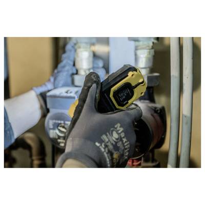 Gehandschoende arbeider die een gele infraroodthermometer gebruikt om een pijp of motor in een industrieel nutsbedrijfsgebied te controleren.