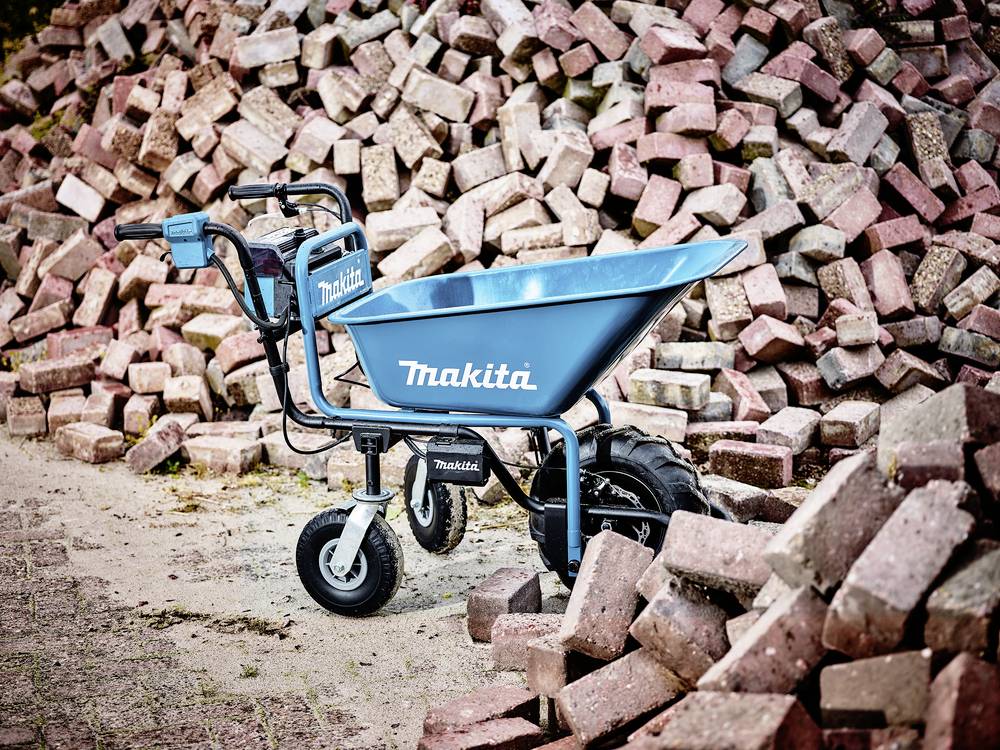 Elektrische kruiwagen van Makita voor een grote stapel rode bakstenen, die kunnen worden gebruikt voor bouw- of tuinwerkzaamheden.