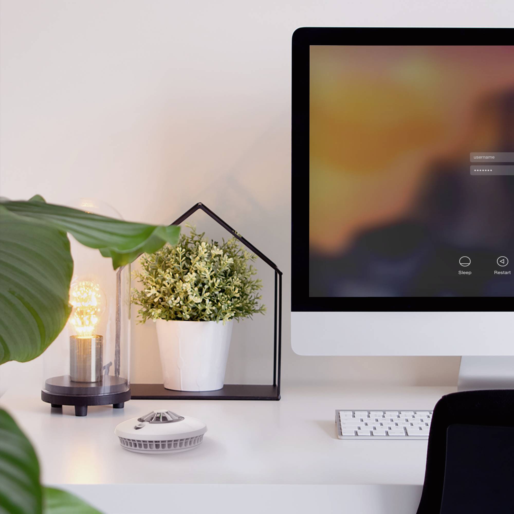 Een stijlvolle schrijftafel met een moderne computer, een wit toetsenbord en een decoratieve plant in een witte pot.
