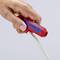 Een hand houdt een rood Knipex-gereedschap vast dat wordt gebruikt om een wit kabel te strippen.