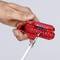 Een hand houdt een rood gereedschap vast dat wordt gebruikt om een wit kabel te strippen.