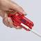 Hand houdt rood kabelstriptang vast met een wit kabel erin.
