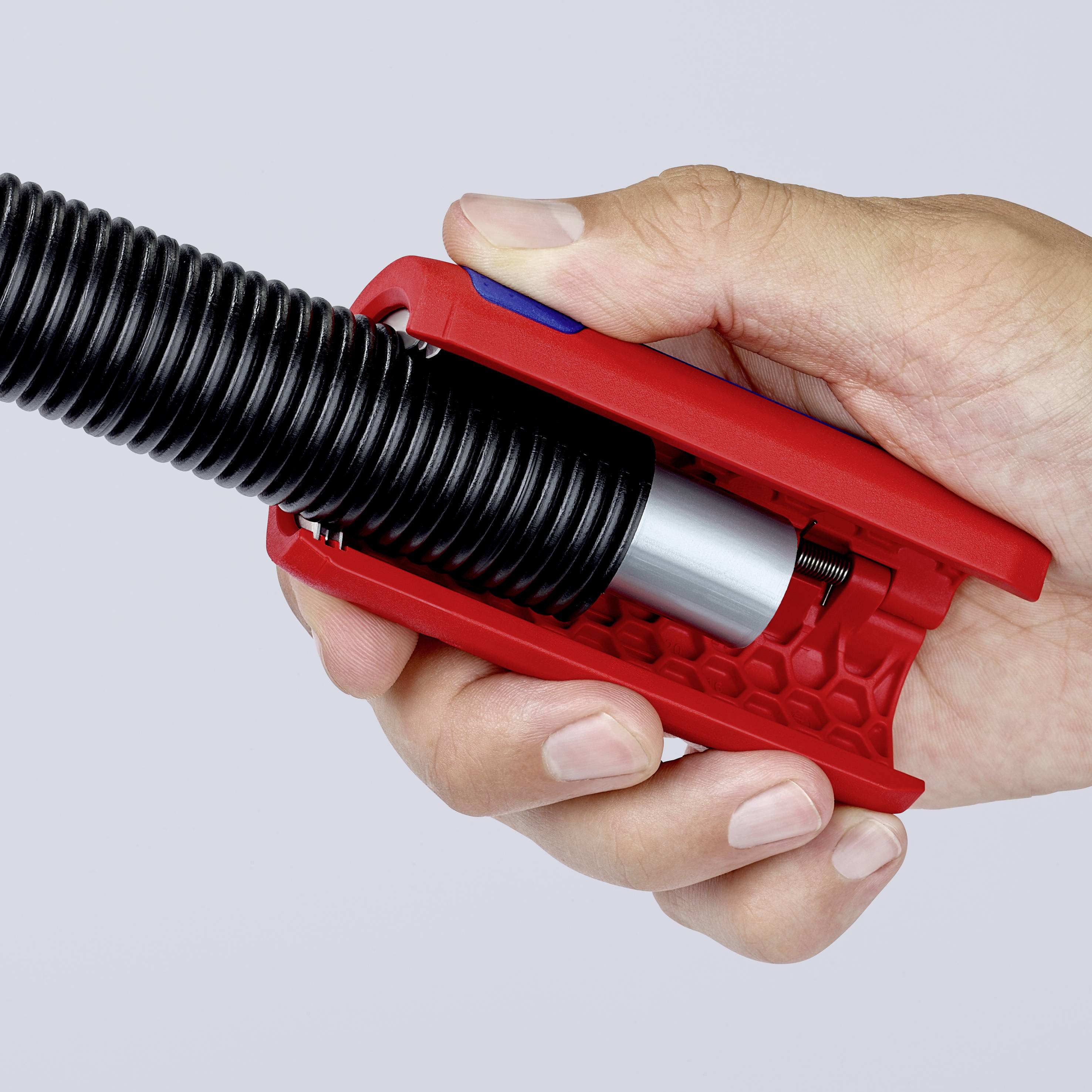 Een hand houdt een rode pepperspray met een zwarte greep en spuitmechanisme. Het ontgrendelingsmechanisme is zichtbaar.