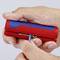 Een persoon gebruikt een rood en blauw gereedschap voor het ontmantelen van kabels met verschillende diameters.