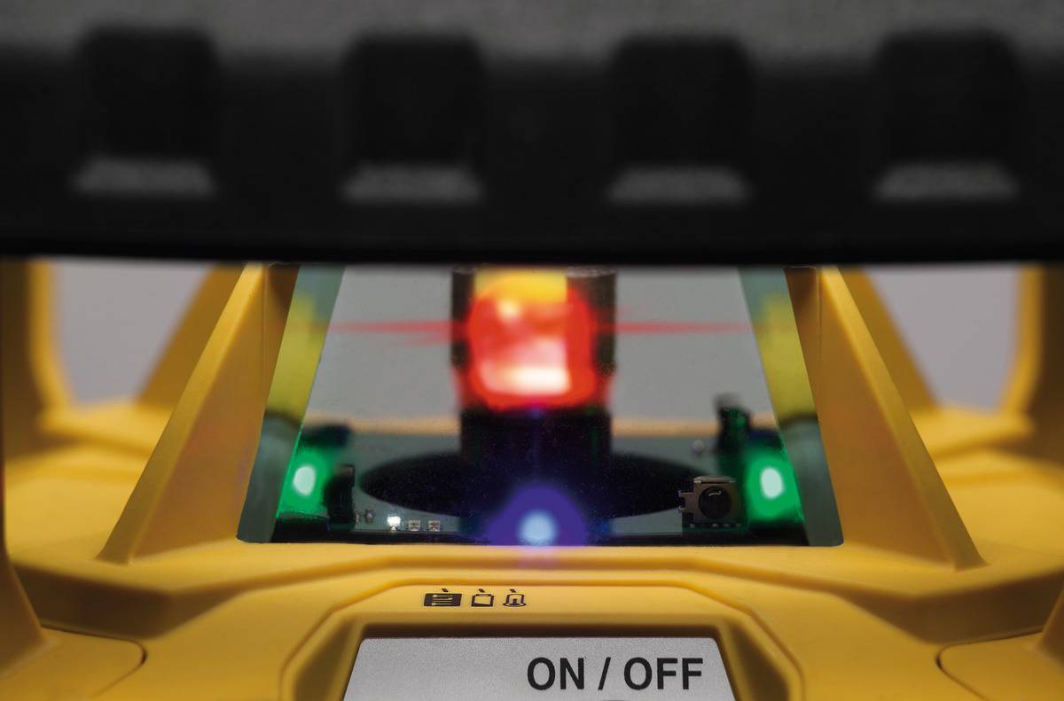 Een gele laserniveaumeeteenheid is geactiveerd en toont een rode laserstraal. Voorzijde met 'AAN/UIT'-schakelaar zichtbaar.