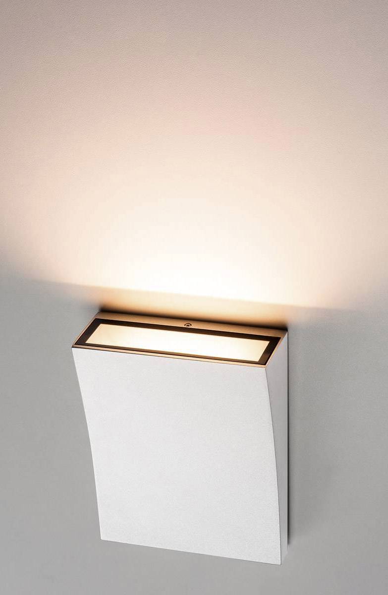 Een moderne wandlamp met rechthoekig ontwerp die naar boven schijnt en warm licht op de muur creëert.
