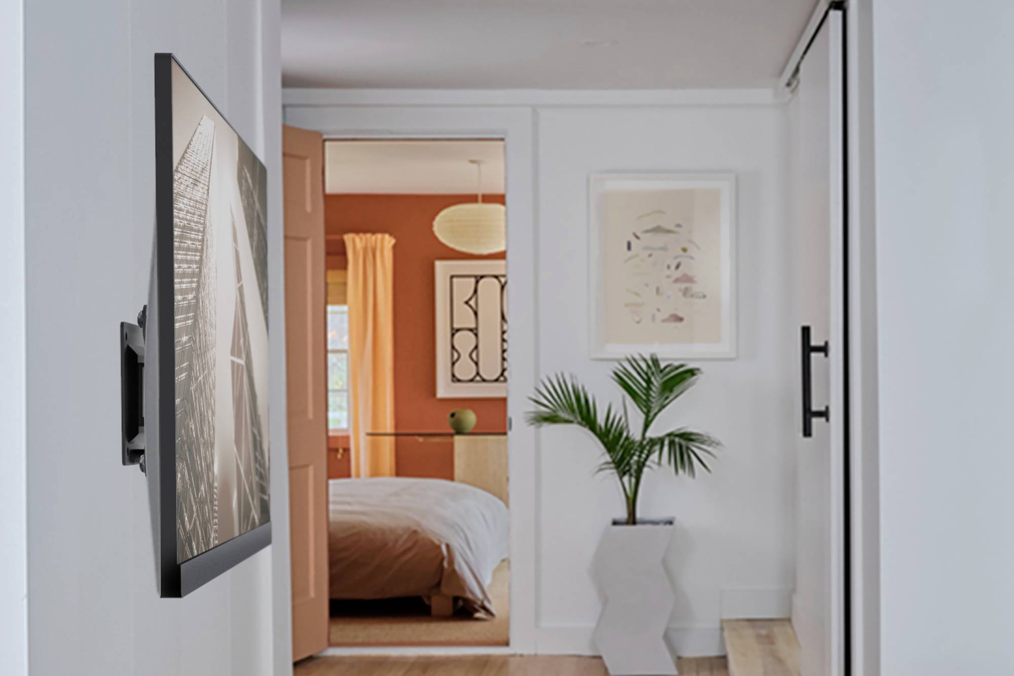 Een moderne gang met een ingelegd wandschilderij leidt naar een slaapkamer met oranje muren en witte meubels. Een palmboom staat ervoor.