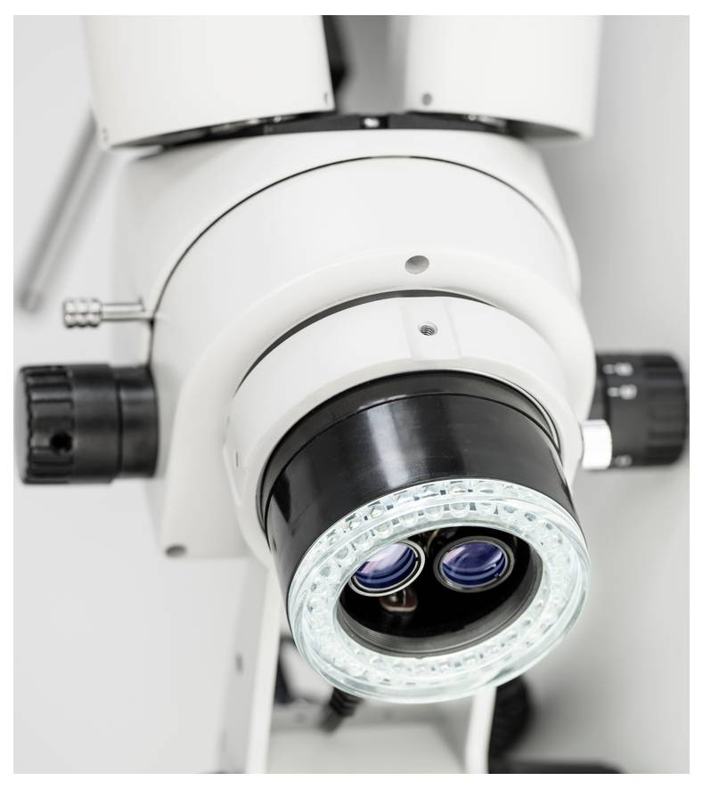 Een microscoop-oculair van bovenaf gefotografeerd, toont twee lenzen en een cirkelvormige verlichting, klaar voor wetenschappelijk onderzoek.