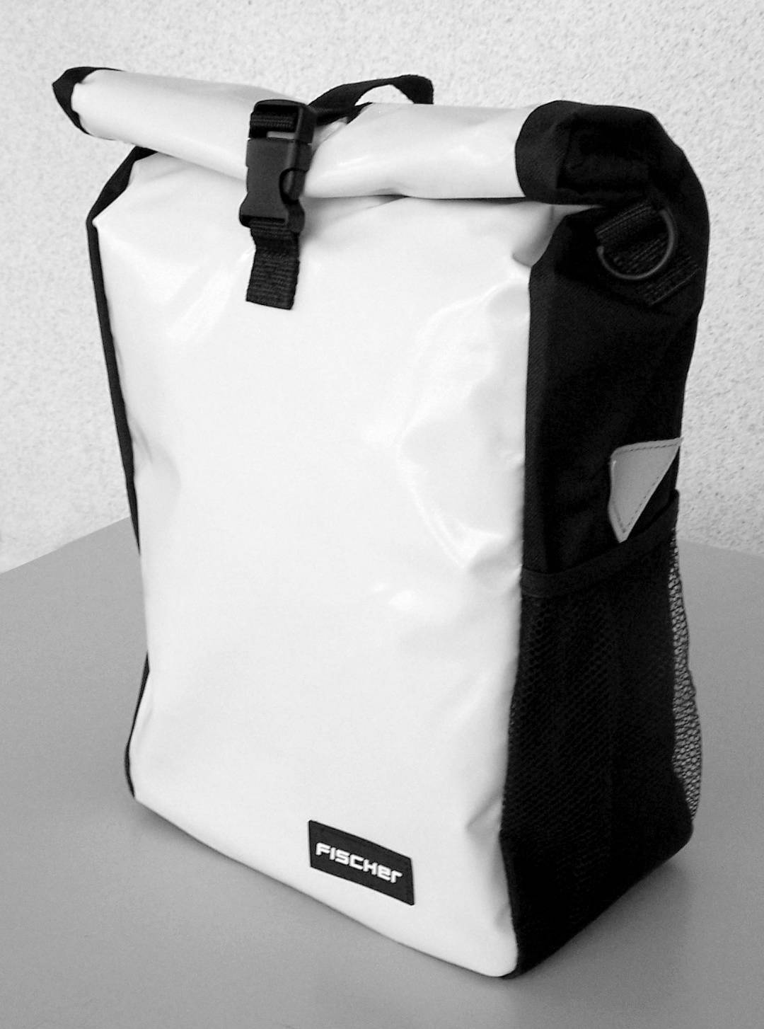 Een witte rugzak met zwarte rand op een tafel. De rugzak heeft een rolltop sluiting met een clip en een mesh zijvak.