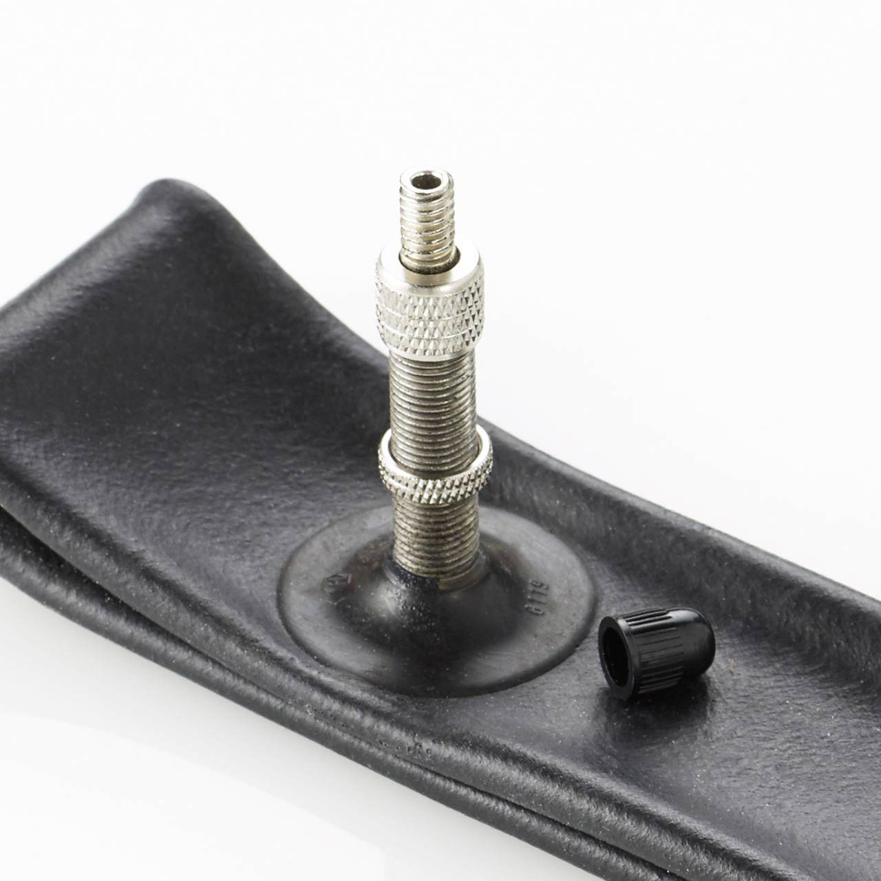 Een fietsbinnenband met metalen schroefdraad en verwijderde plastic dop ligt op een zwarte rubberen slangoppervlakte.