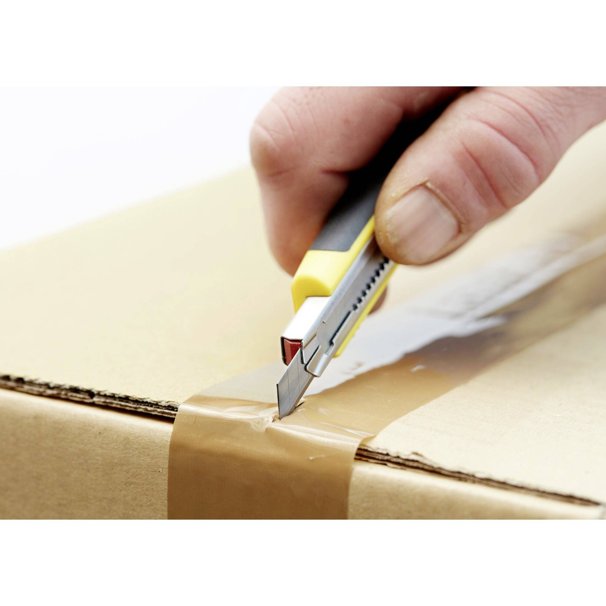 Een hand opent voorzichtig een met plakband verzegelde kartonnen doos met een geel cuttermes.