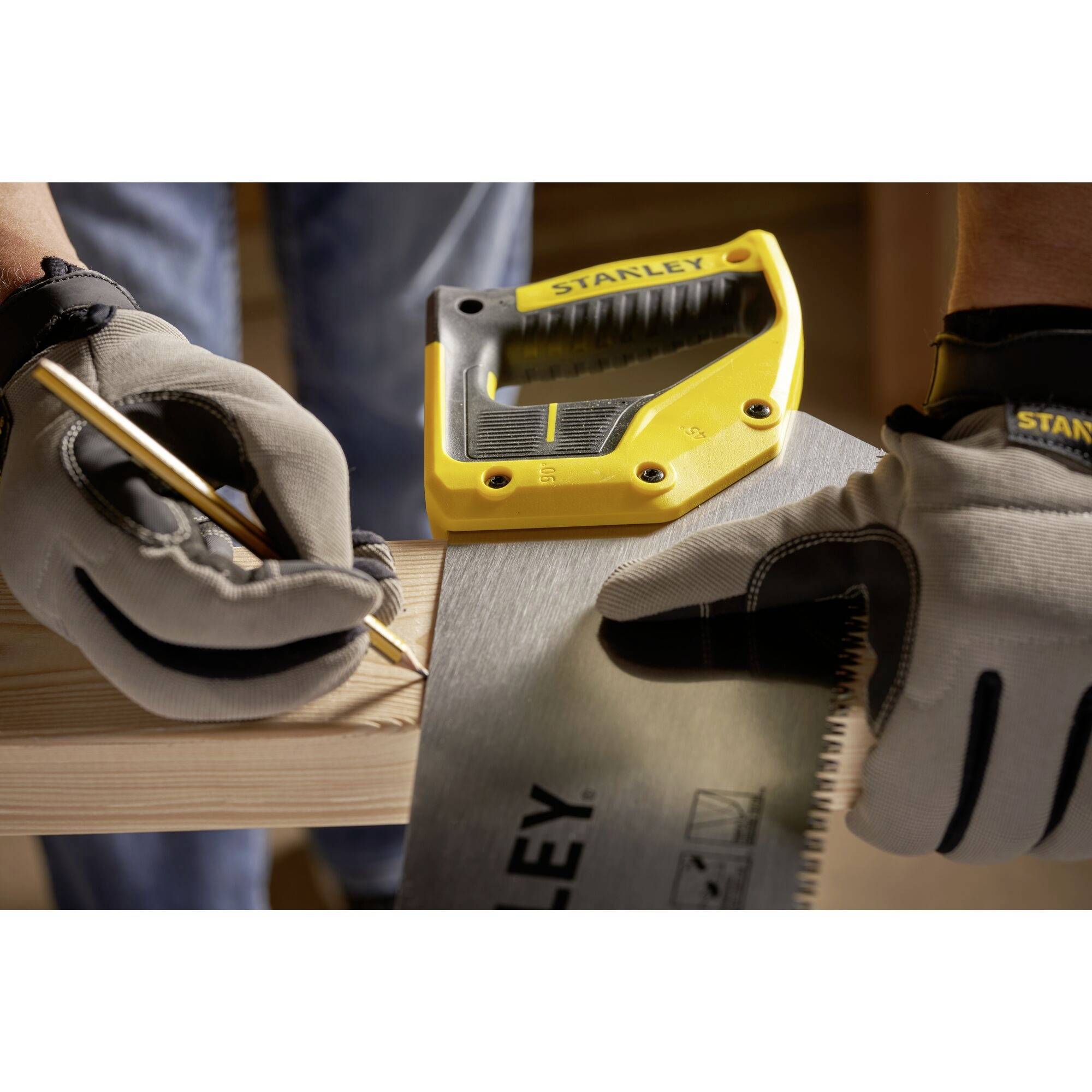 Een persoon met werkhandschoenen tekent een lijn met een potlood op een houten plank en houdt een meetlint vast.