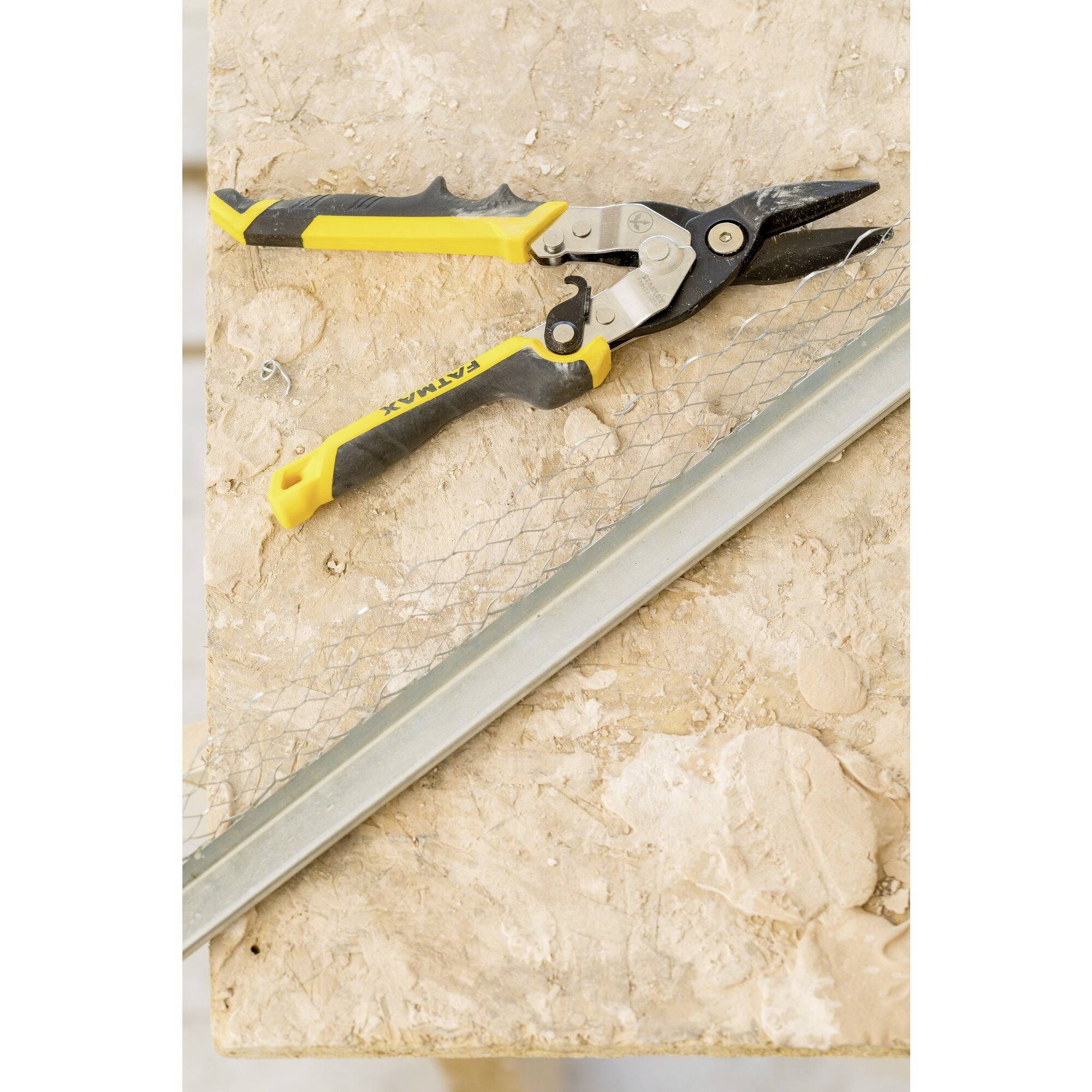 Handschaar op een houten tafel, naast een stuk kippengaas en een metalen strip geplaatst.