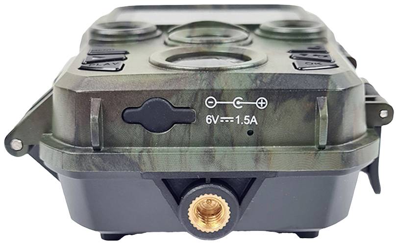 Een wildcamera in camouflage-kleuren toont de aansluitbus en stroomvoorzieningsgegevens '6V - 1.5A' op de voorkant.