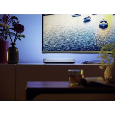 Een televisie toont rustige boten op een meer. De ruimte is sfeervol verlicht, op de voorgrond staat een tafel met een glas thee.