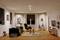 Een modern woonkamer met een bank, fauteuils, tapijten en kunst aan de muren. Het heeft warme verlichting en een houten vloer.