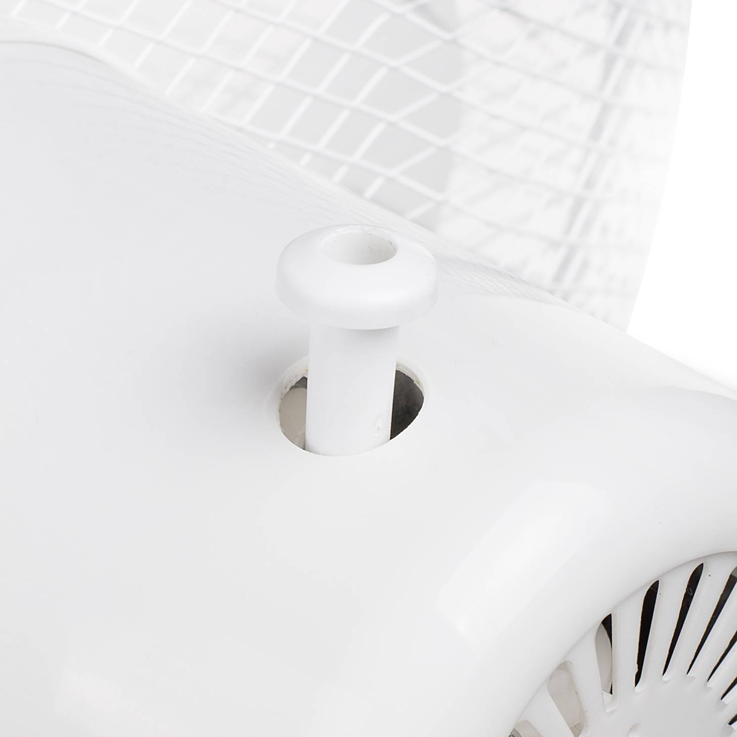 Close-up van een witte tafelventilator die naar links draait. Het beschermrooster en de draaiknop zijn zichtbaar.