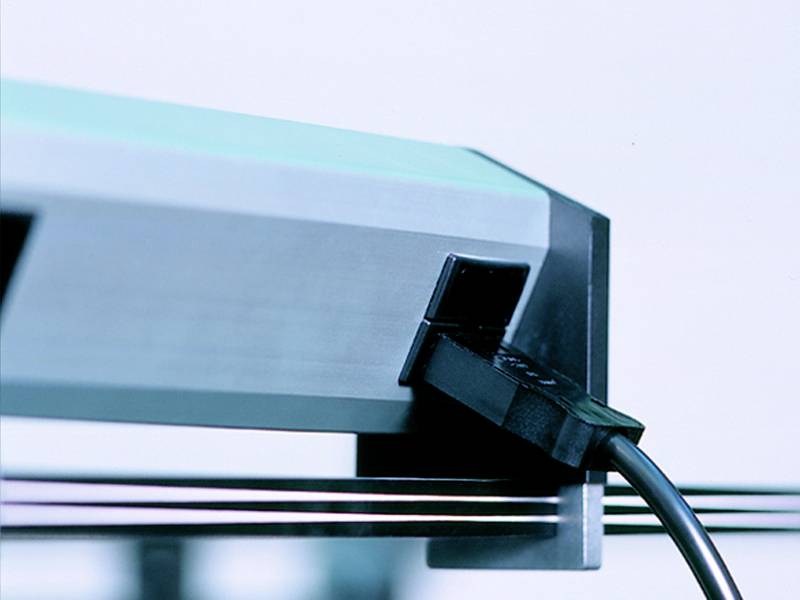 Een zwarte kabelstekker wordt in een aansluiting aan de zijkant van een elektronisch apparaat gestoken, licht schuin gefotografeerd.
