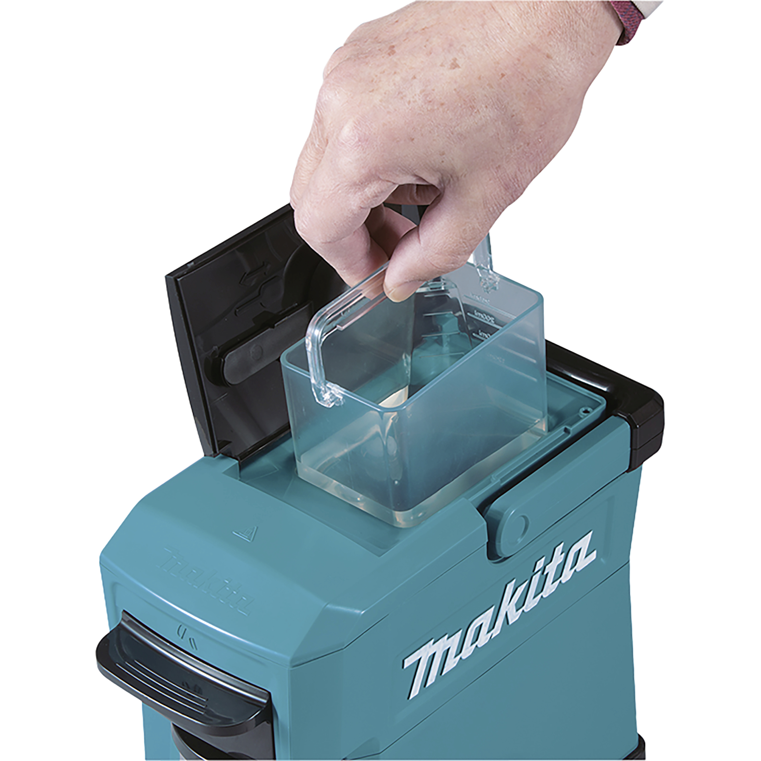 Een hand plaatst een transparante container in de inlaat van een Makita-stofzuiger, gefotografeerd tijdens onderhoud of reiniging van het apparaat.