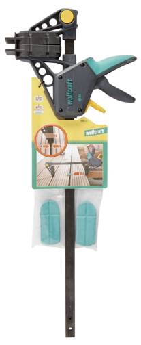 Een Wallcraft snelspanklem met ergonomische greep, waarbij de bijgevoegde verpakking twee groene pads bevat en het gebruik in houtbewerking illustreert.