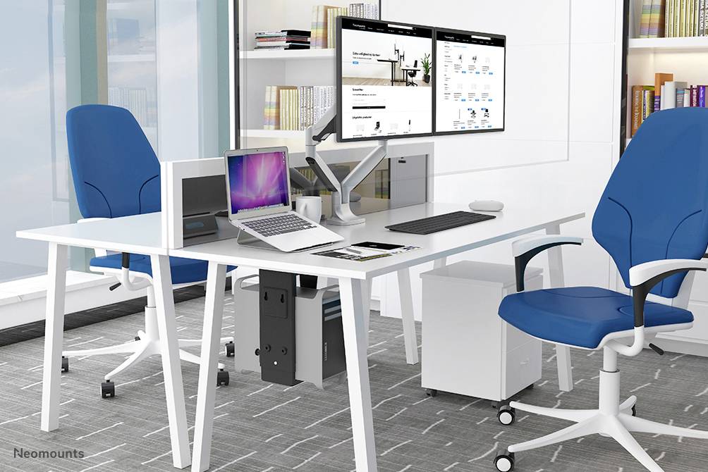 Modern kantoor met twee blauwe bureaustoel, witte tafel, twee monitors, laptop en boeken in het rek. Lichte en opgeruimde sfeer.