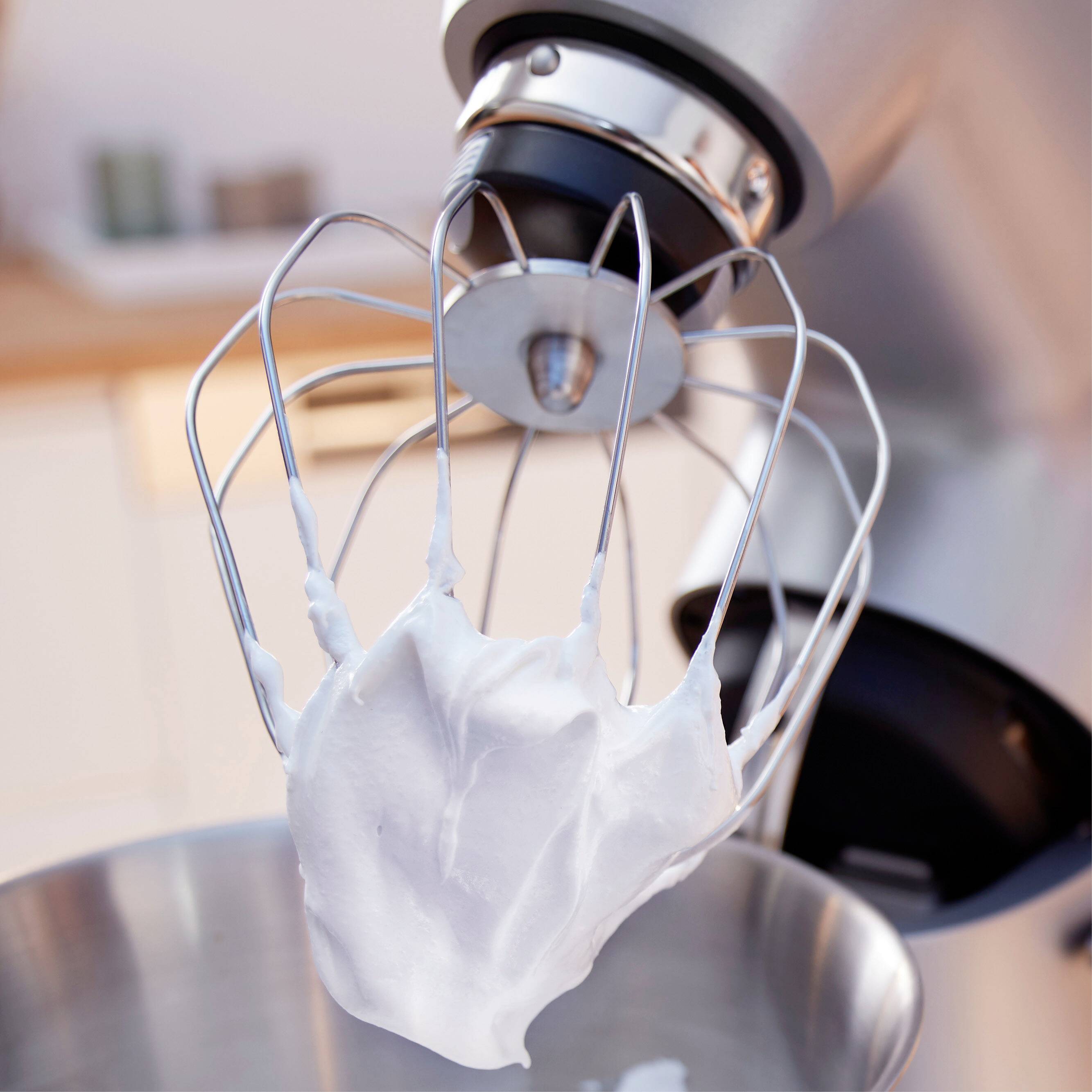 Een elektrische mixer klopt eiwit tot stevige schuim in een moderne keuken.