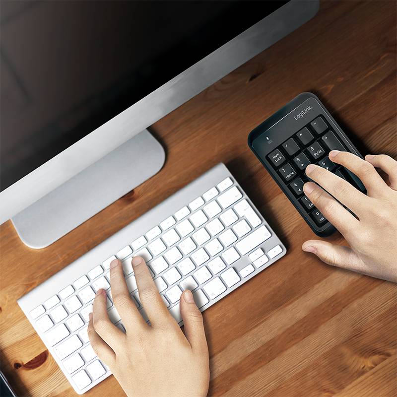 Een persoon typt op een aparte numerieke toetsenblok naast een computertoetsenbord. De monitor is zichtbaar op de achtergrond.