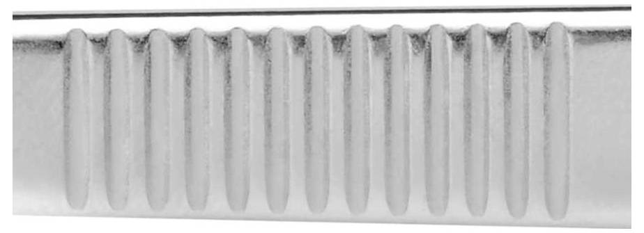 Zilveren metalen voorwerp met gegroefde oppervlakte, vermoedelijk onderdeel van een gereedschap of keukengerei, in close-up.