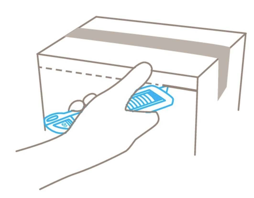 Een hand steekt een pakbon in de gleuf van een pakket aan een balie.