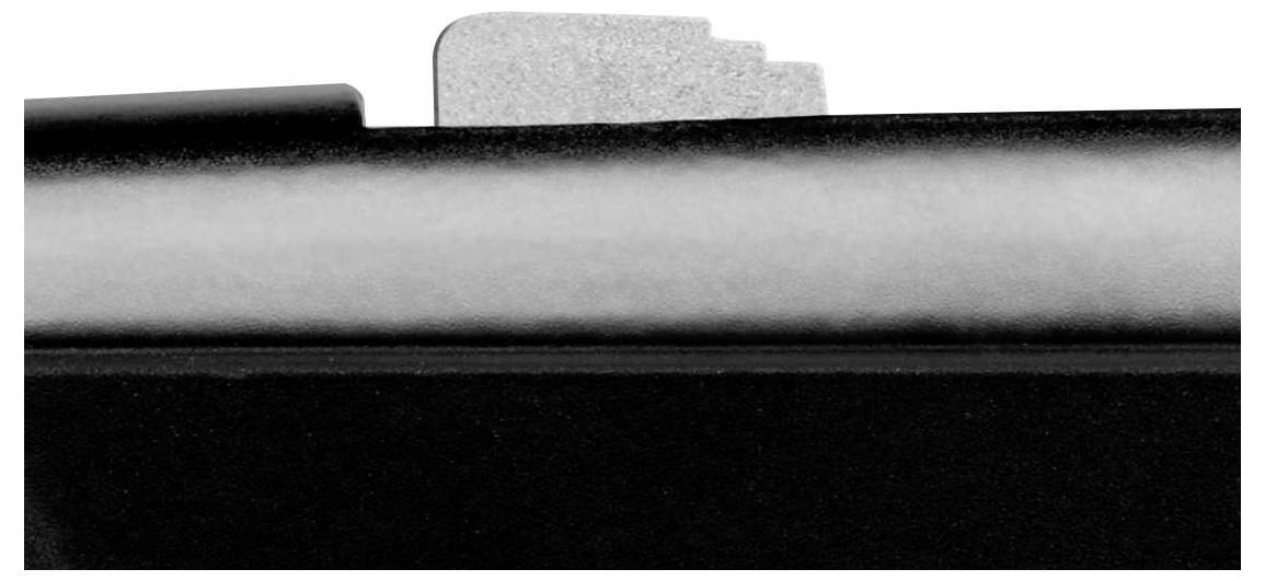 Close-up van een metalen onderdeel, waarschijnlijk een schuiver of hefboom, op een zwart oppervlak.