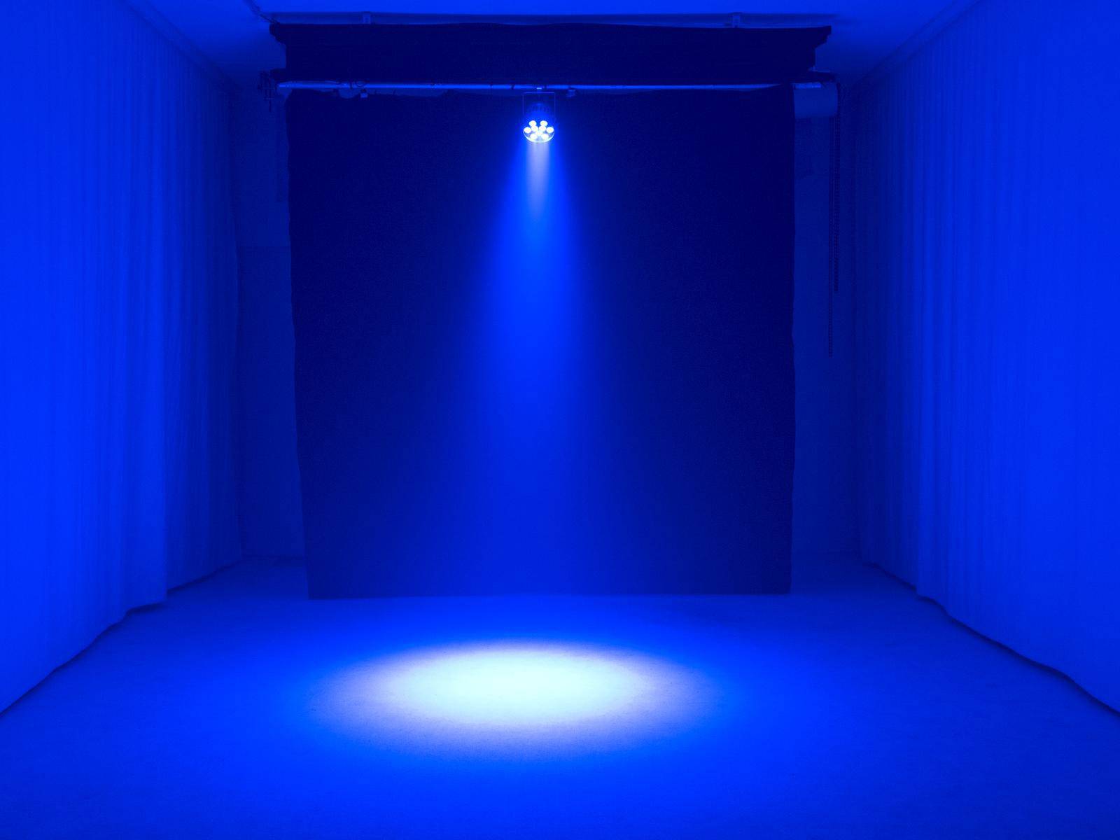Een blauwe, lege ruimte met een helder schijnsel midden in de ruimte, dat de vloer verlicht in een heldere, ronde zone.