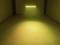 Een sobere ruimte met warm geel licht dat uitstraalt van een klein podium met schijnwerpers, een minimalistische omgeving.