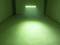 Een ruimte met groene verlichting, afkomstig van een frame met meerdere LED-lampen, verlicht een oppervlak op de vloer.